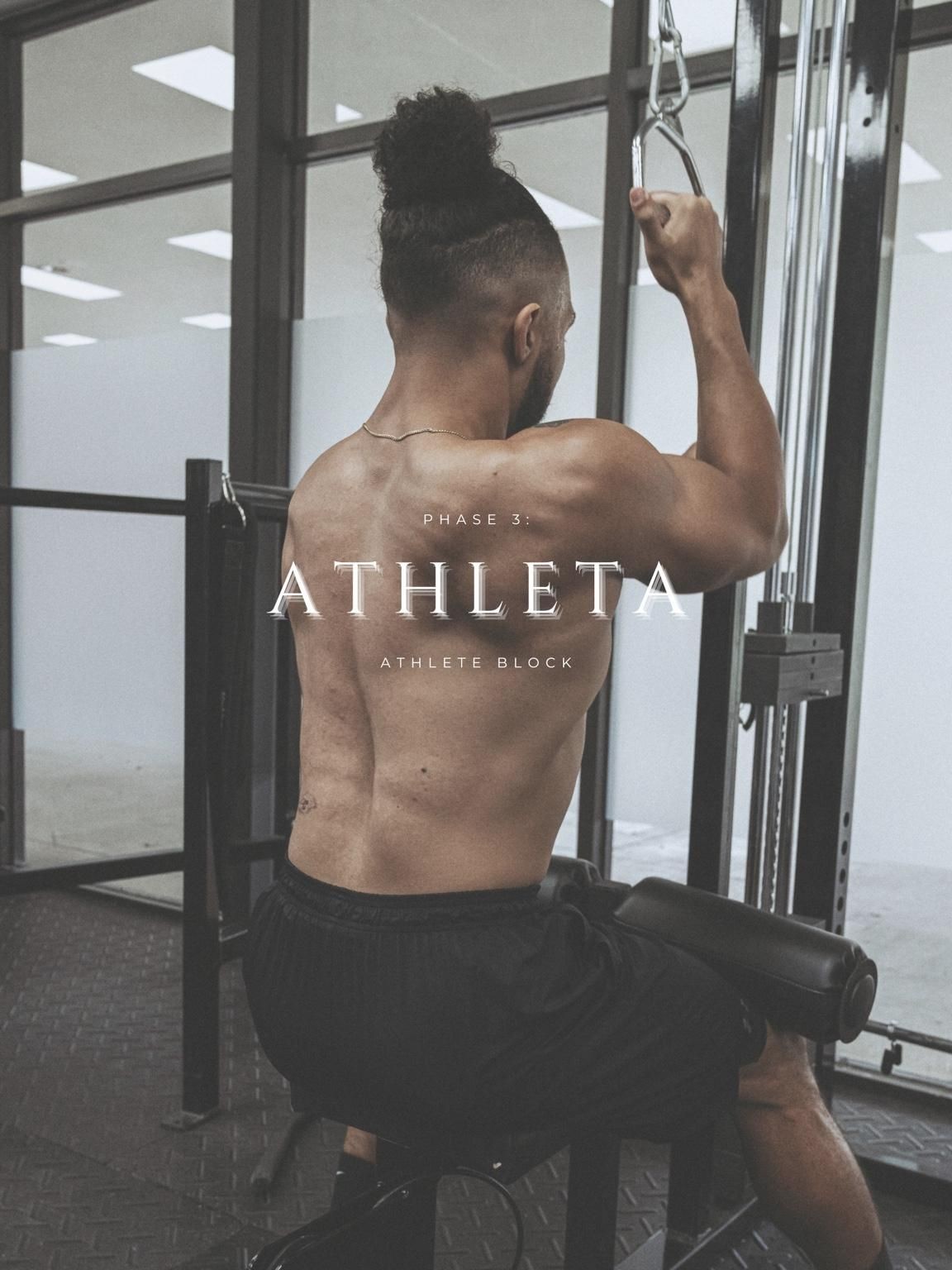 Back view of a shirtless man exercising on a cable machine in a gym.